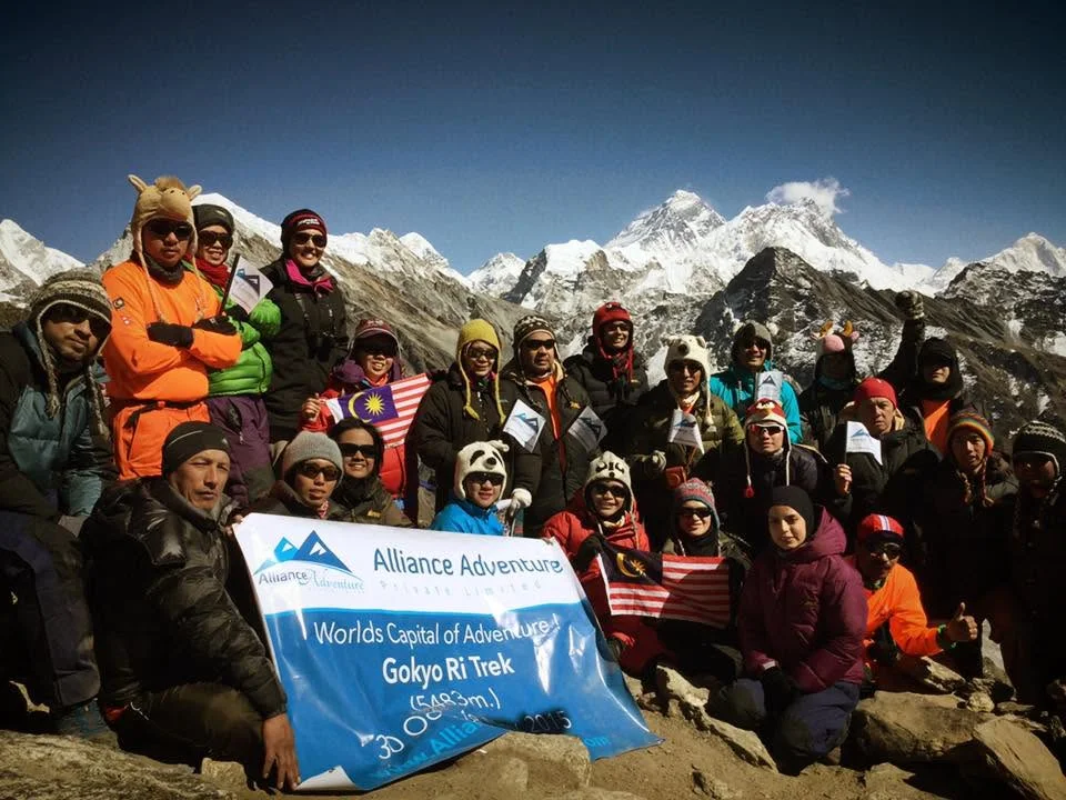 Mountain trekking group holding an Alliance Adventure banner