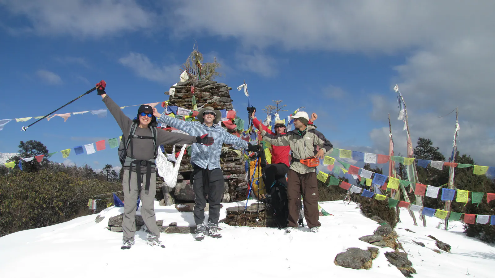Trekkers celebrating beside prayer flags on the Fikuri trail